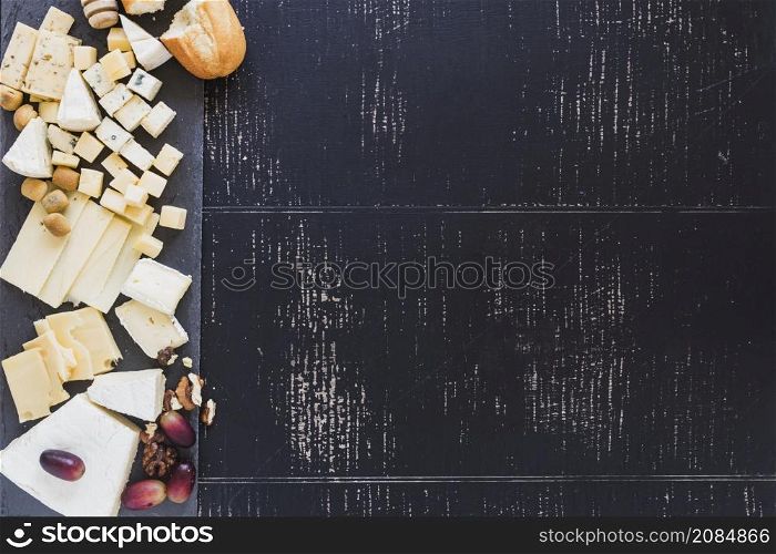 overhead view bread with different type cheese with grapes black textured backdrop