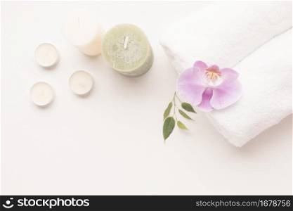 overhead view candle with orchid flower rolled up towel