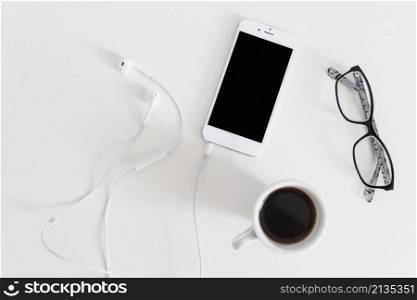 overhead view cellphone with connected earphone coffee cup eyeglasses