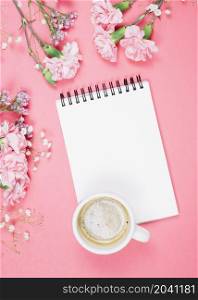 overhead view coffee cup blank notepad with carnations gypsophila limonium flowers pink background