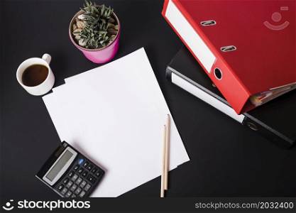 overhead view coffee cup calculator pot plant blank white papers pencils paper files black background