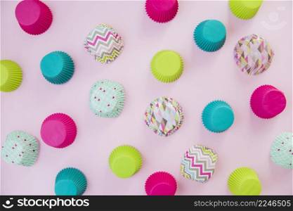 overhead view colorful cupcake paper cups pink backdrop