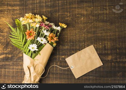 overhead view delicate flower bunch brown paper tag wooden surface
