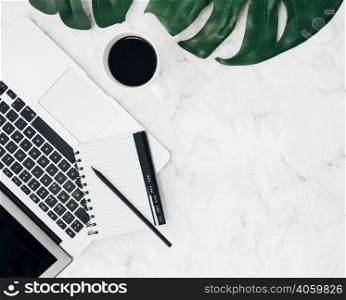 overhead view diary pencil laptop coffee cup monstera leaf marble backdrop