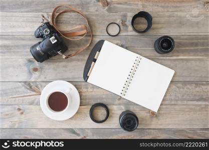 overhead view dslr camera cup tea spiral notepad pen camera lens extension rings wooden background