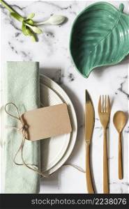 overhead view folded napkin tied with tag ceramic plate cutlery marble textured background