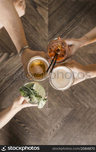 overhead view friend hands toasting drinks