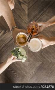 overhead view friend hands toasting drinks