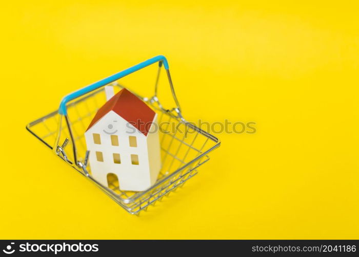 overhead view house model inside shopping cart against yellow background