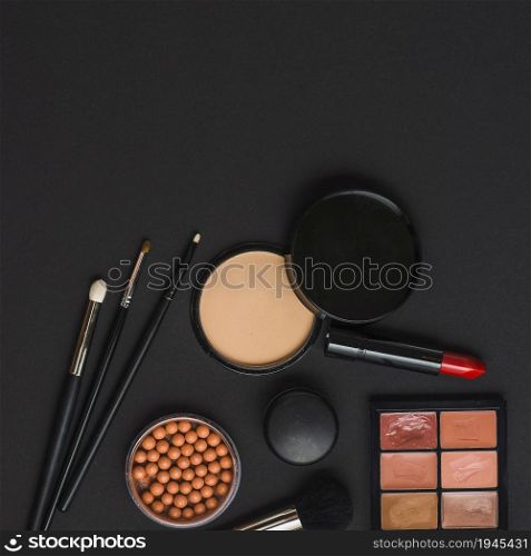 overhead view makeup products with brushes black backdrop. High resolution photo. overhead view makeup products with brushes black backdrop. High quality photo