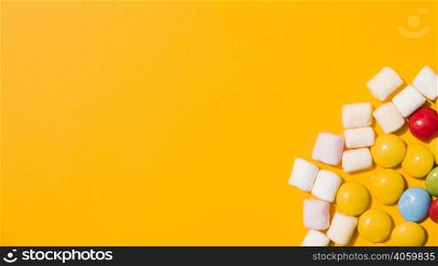 overhead view marshmallow colorful candies yellow background
