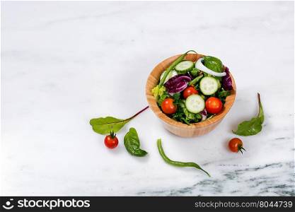 Overhead view of a bowl of fresh salad on marble stone