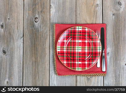 Overhead view of a festive Christmas dinner setting and cloth place mat on top of rustic wood