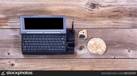 Overhead view of a vintage computer on stressed wood with stone fossils. Obsolete concept.