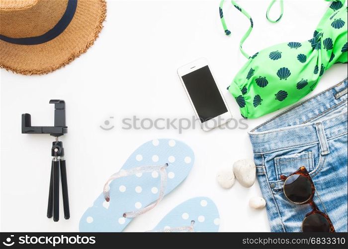 Overhead view of beach items and smart phone, Summer concept on white background with copy space, Flat lay