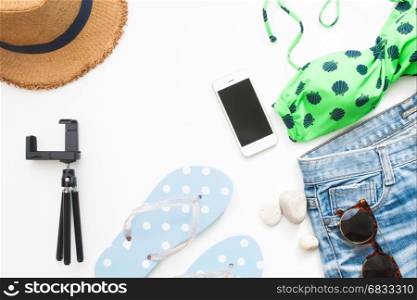 Overhead view of beach items and smart phone, Summer concept on white background with copy space, Flat lay
