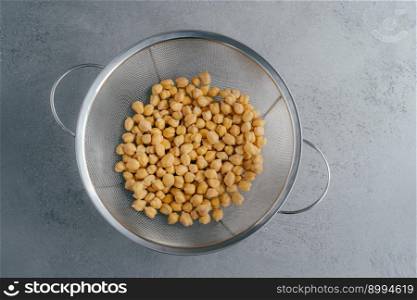 Overhead view of chickpeas in sieve against grey background. Legumes for vegans. Organic dish. Healthy eating concept. Vegetarianism