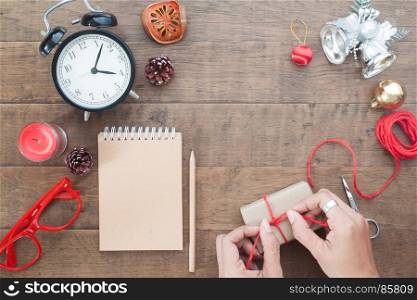 Overhead view of Christmas and Thanksgiving concept, Woman hands decorating gift box on wooden background