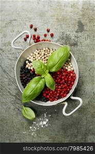 Overhead view of colourful dried pepper mix and basil in bowl on rustic background