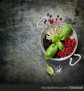 Overhead view of colourful dried pepper mix and basil in bowl on rustic background