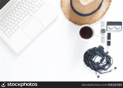 Overhead view of computer laptop, a cup of coffee and woman accessories on white background with copy space