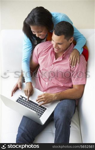 Overhead View Of Couple Relaxing On Sofa Using Laptop