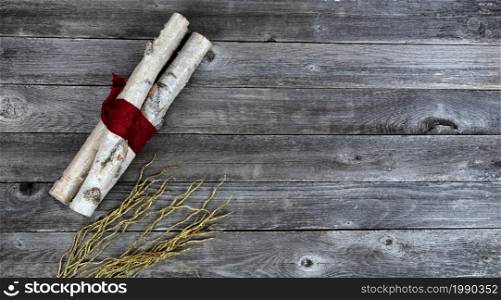 Overhead view of decorated white birch logs wrapped in red cloth and flaming golden pattern decorations on aged wooden planks for a Merry Christmas background