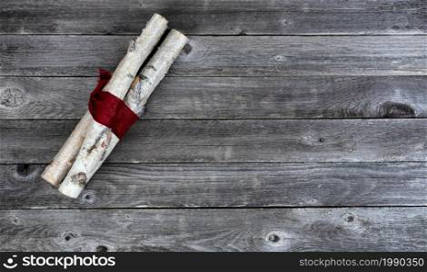 Overhead view of decorated white birch logs wrapped in red cloth on aged wooden planks for a Merry Christmas background