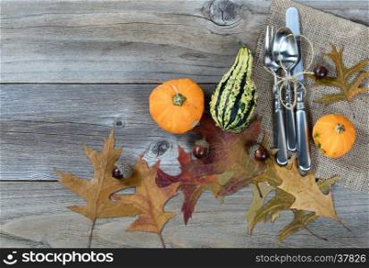 Overhead view of dinner setting for Thanksgiving Autumn holiday in horizontal layout on rustic wooden boards.