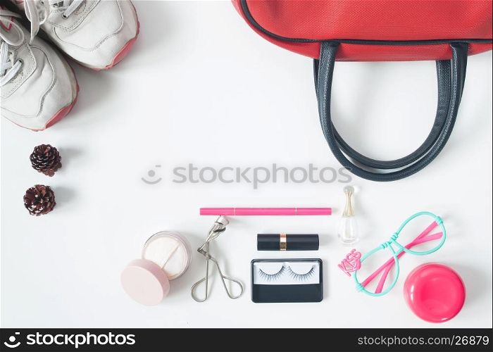 Overhead view of essential beauty items, Top view of red hand bag, fashion eyeglasses, cosmetics and sneakers, top view isolated on white background