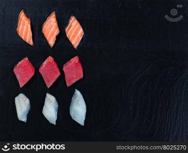 Overhead view of fresh Japanese sushi on black slate. Horizontal layout with plenty of copy space.