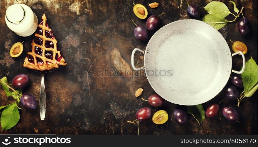 overhead view of fresh plum pie or tart and plums on dark rustic background