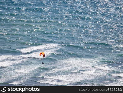 Overhead view of hang glider over rough ocean off Hawaii