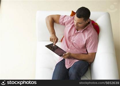 Overhead View Of Man Relaxing On Sofa Using Digital Tablet