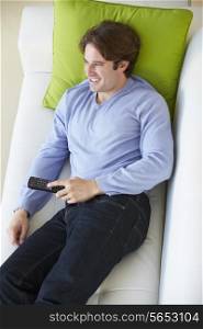 Overhead View Of Man Relaxing On Sofa Watching Television