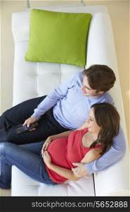 Overhead View Of Man Relaxing On Sofa With Pregnant Wife
