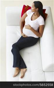 Overhead View Of Pregnant Woman Relaxing On Sofa