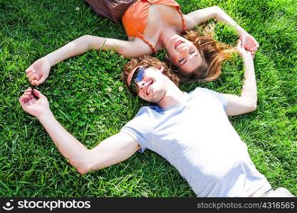 Overhead view of romantic young couple lying on garden lawn