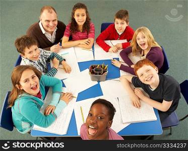 Overhead View Of Schoolchildren Working Together At Desk With Teacher