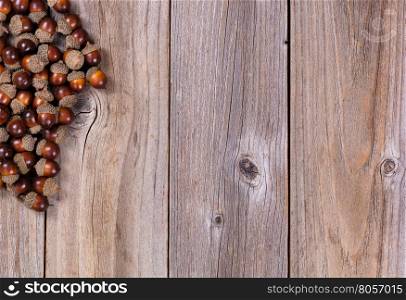 Overhead view of seasonal autumn acorn decorations, upper left corner, on rustic wooden boards.