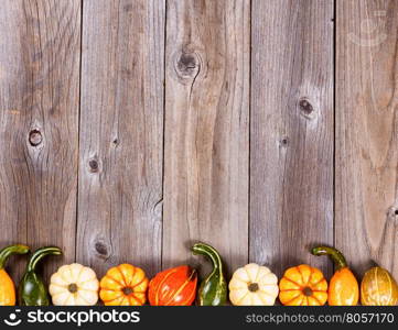 Overhead view of seasonal autumn gourd decorations, lower border, on rustic wooden boards.