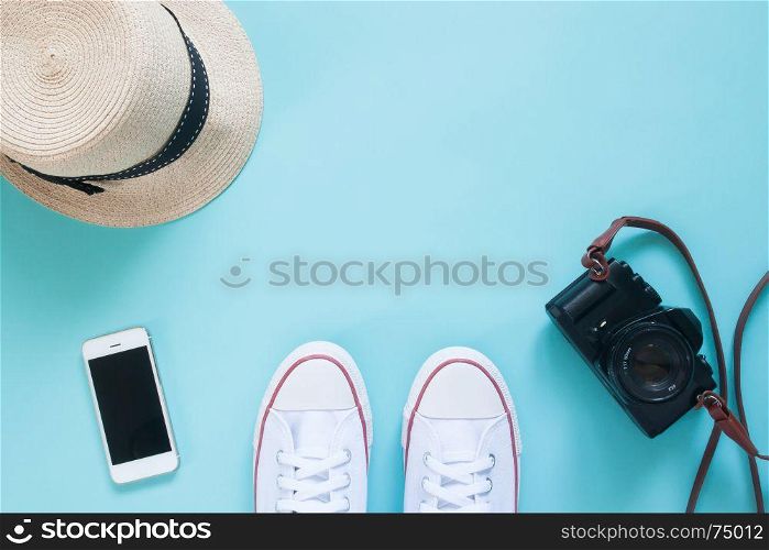 Overhead view of selfie of sneakers with smartphone, camera and hat on pastel color floor