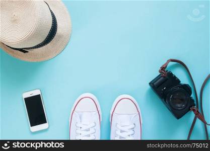 Overhead view of selfie of sneakers with smartphone, camera and hat on pastel color floor