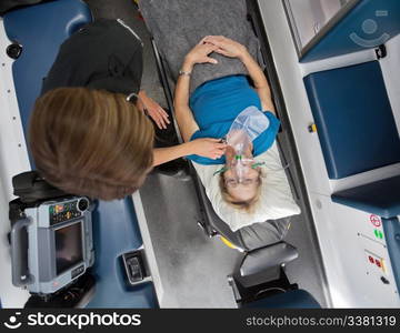 Overhead view of senior woman patient in ambulance receiving oxygen and having heart rate measured