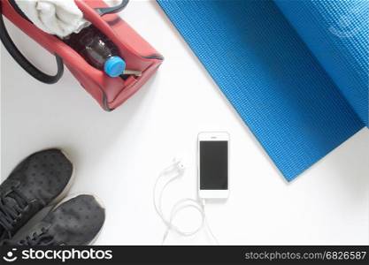 Overhead view of sport equipment and smartphone on blue yoga mat on white background, Isolated on white with copy sapce