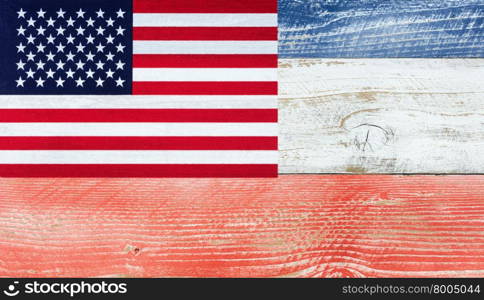 Overhead view of United States of America flag, upper left hand corner, on wooden planks painted in national colors of red, white, blue. Patriotic concept.