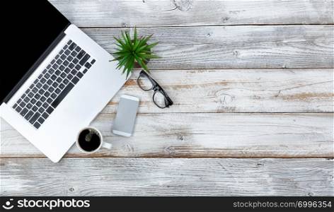 Overhead view of working desktop and smart phone, coffee, reading glasses and baby plant with plenty of copy space