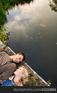 Overhead view of young couple lying on river footbridge
