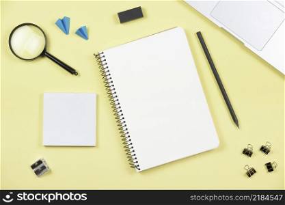 overhead view office supplies with laptop yellow background