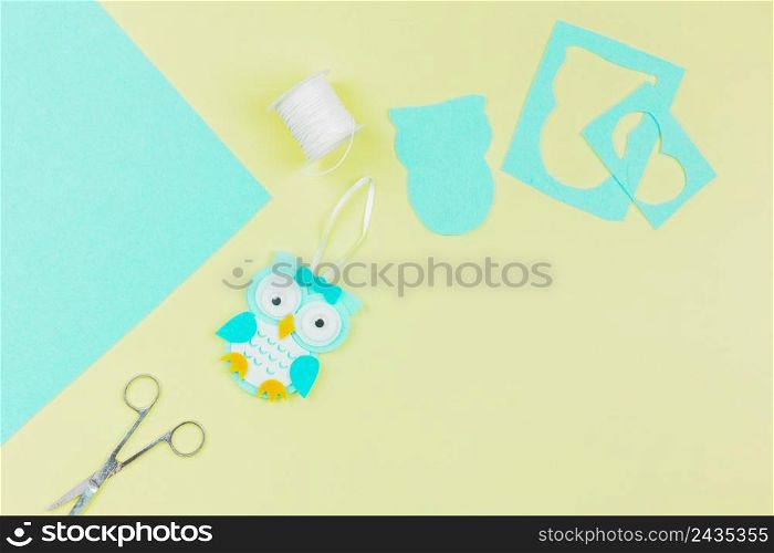 overhead view paper owl with thread spool scissor yellow background
